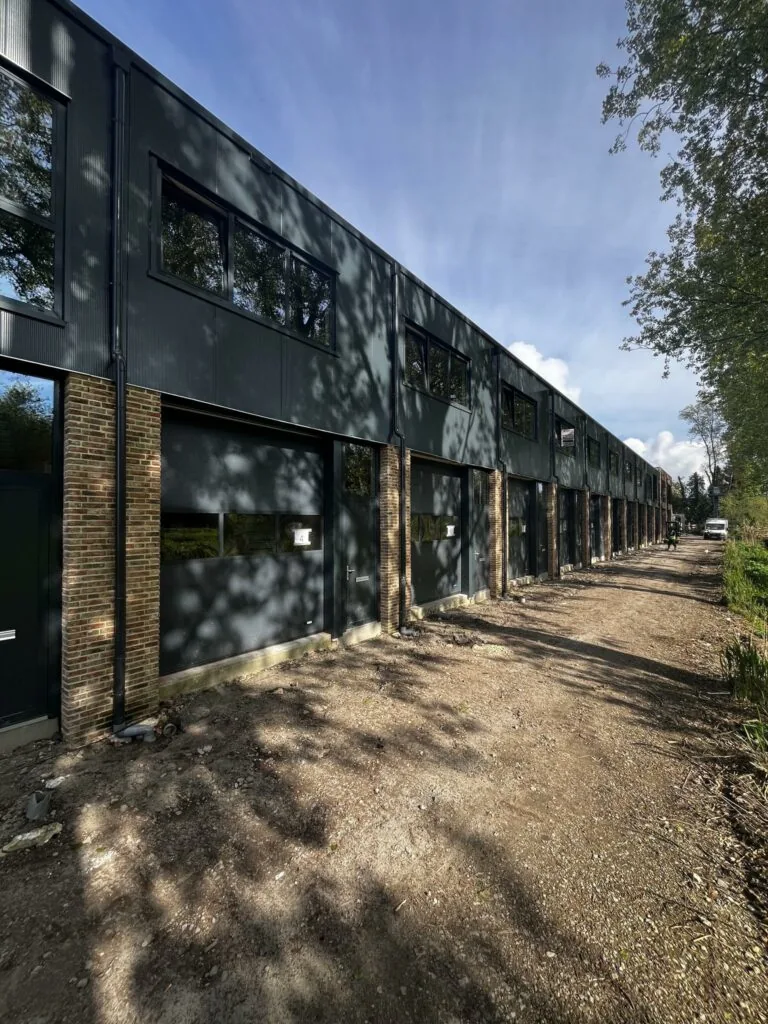 Nieuwbouw bedrijfsunits aan de Broekdijk West, gefotografeerd vanaf een onverharde weg op een zonnige dag.